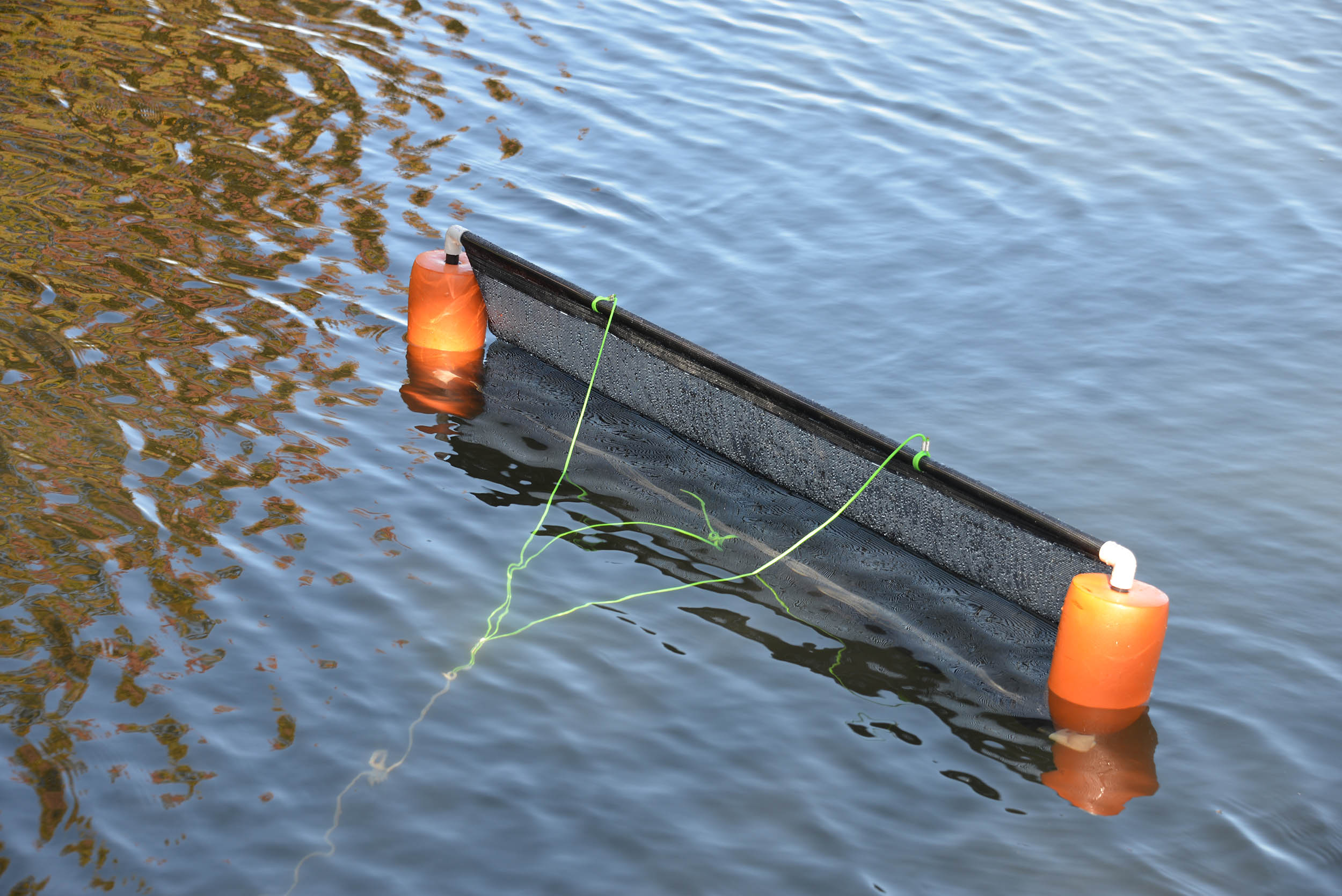 Owner pulling the pond skimmer across the water from shore